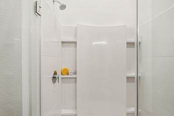 A white bathroom with a shower head and a towel rack